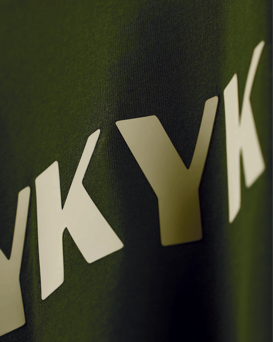 Olive T-shirt with IYKYK text, angled close-up detail view