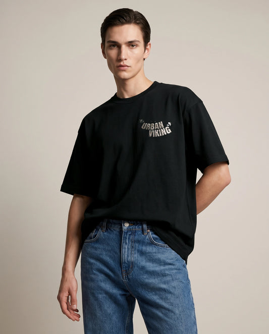 Female model wearing black oversized t-shirt with Urban Viking text logo on chest, front view