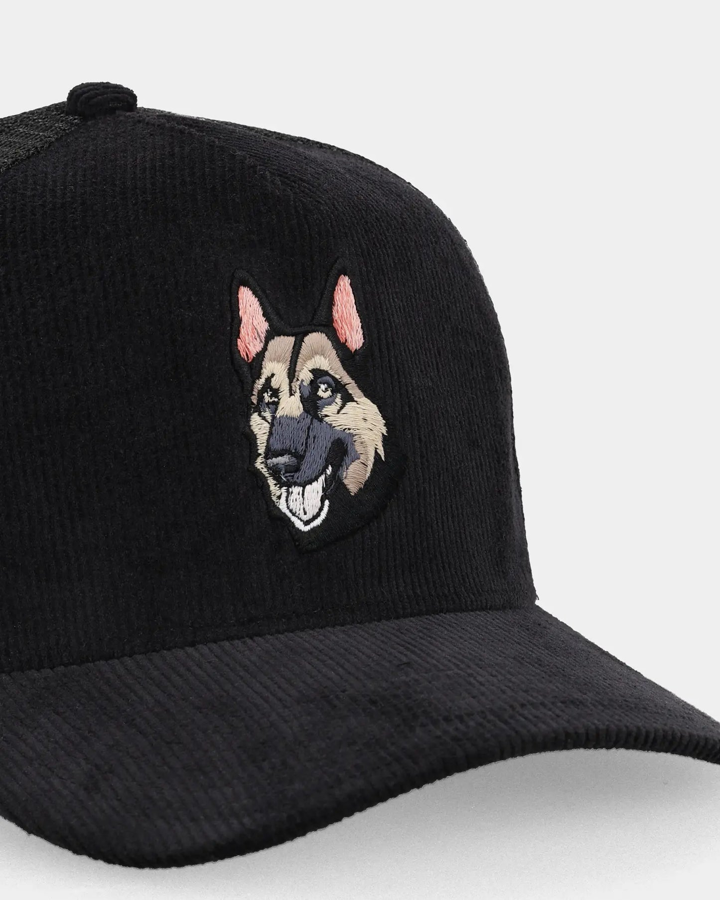 Black trucker cap with Alpha Shepherd patch, angled front detail view
