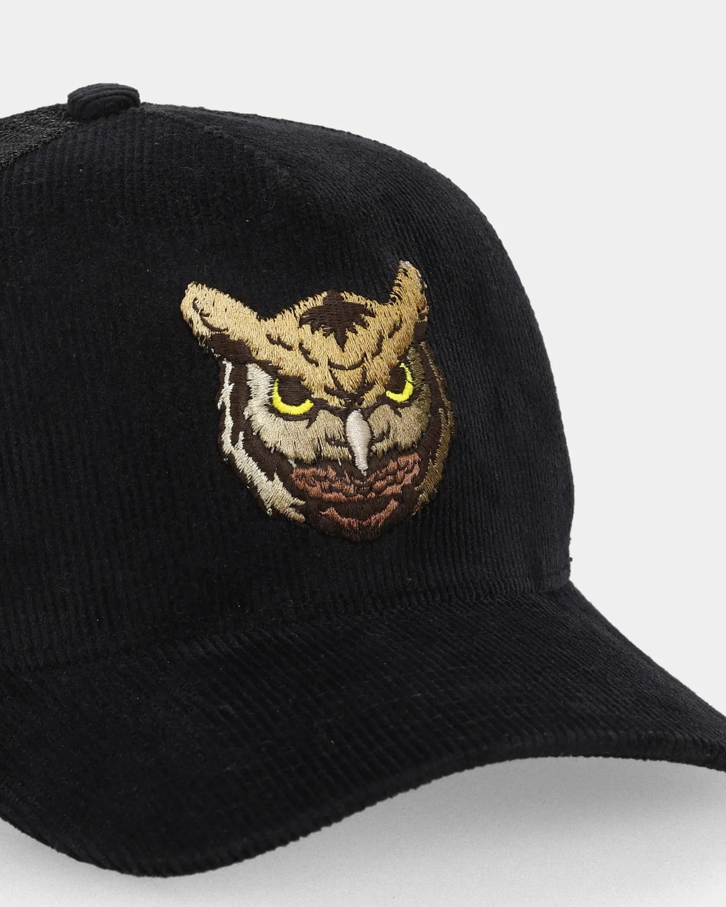 Black trucker cap close-up with phantom owl embroidery detail