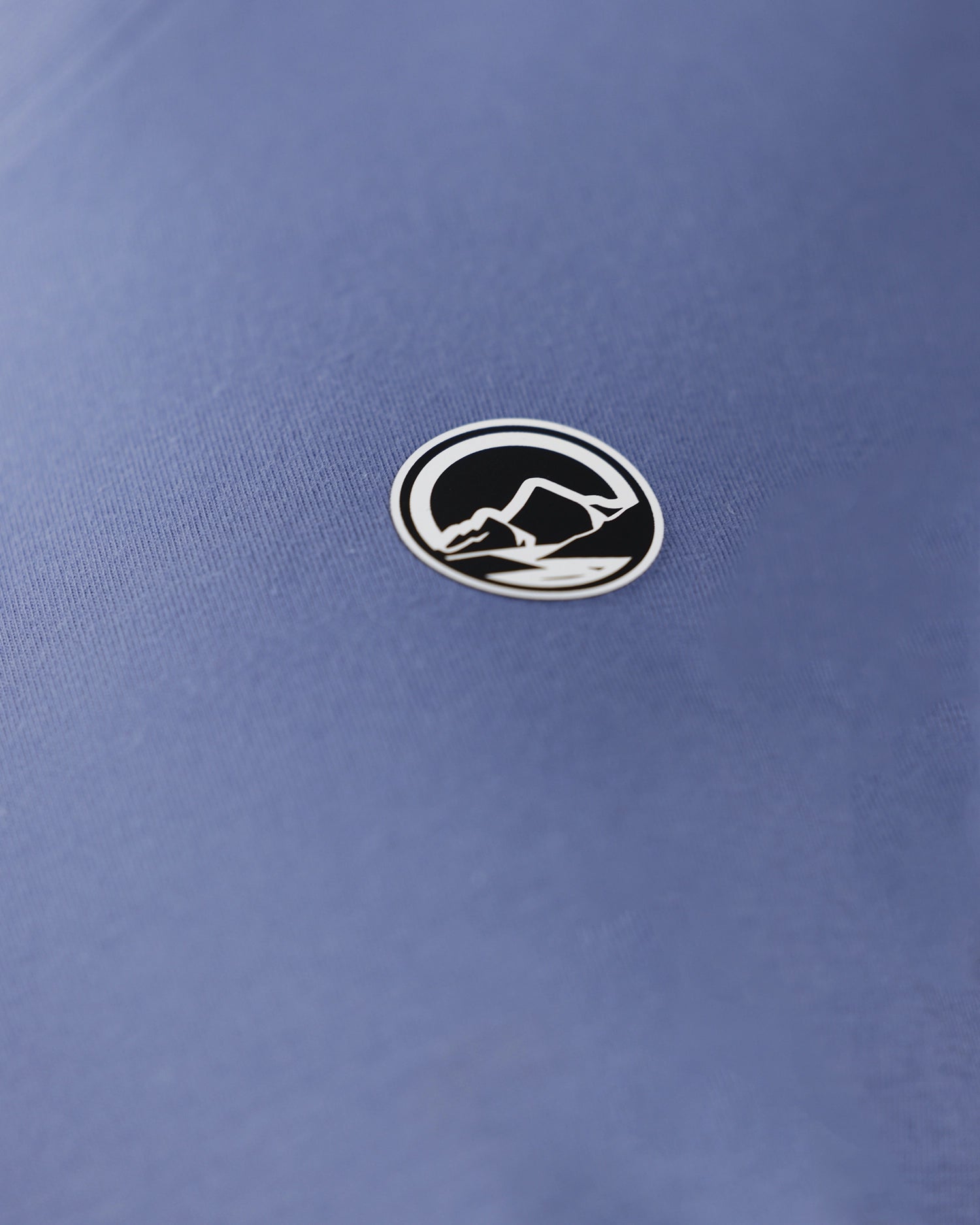Close-up of round mountain logo patch on blue fabric, detail shot
