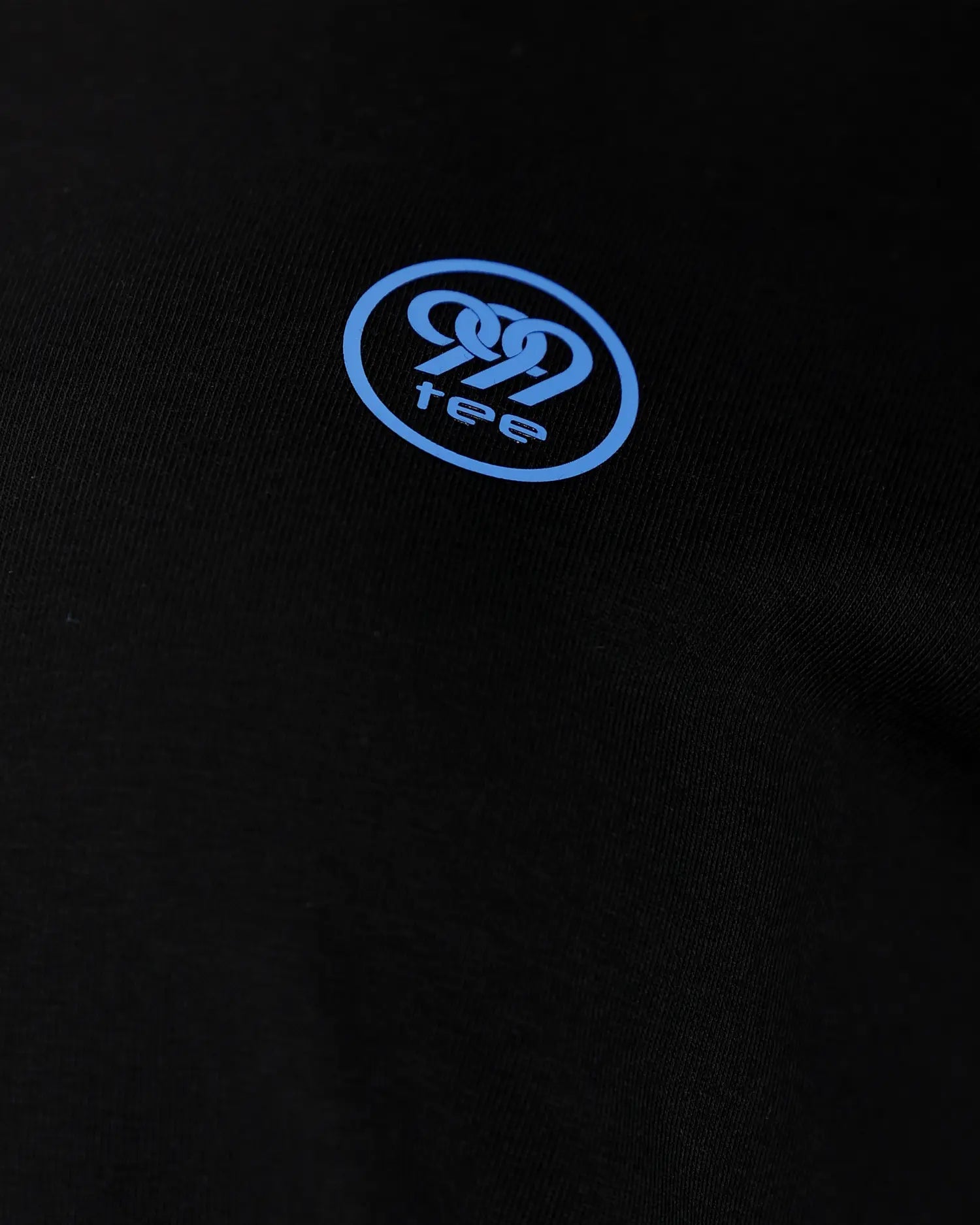 Close-up of blue 999tee logo print on black fabric, detail shot
