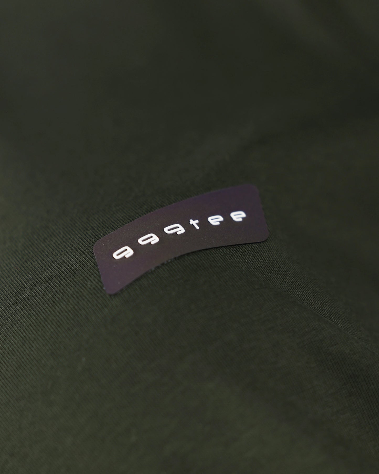 999tee fabric label close-up on olive apparel detail
