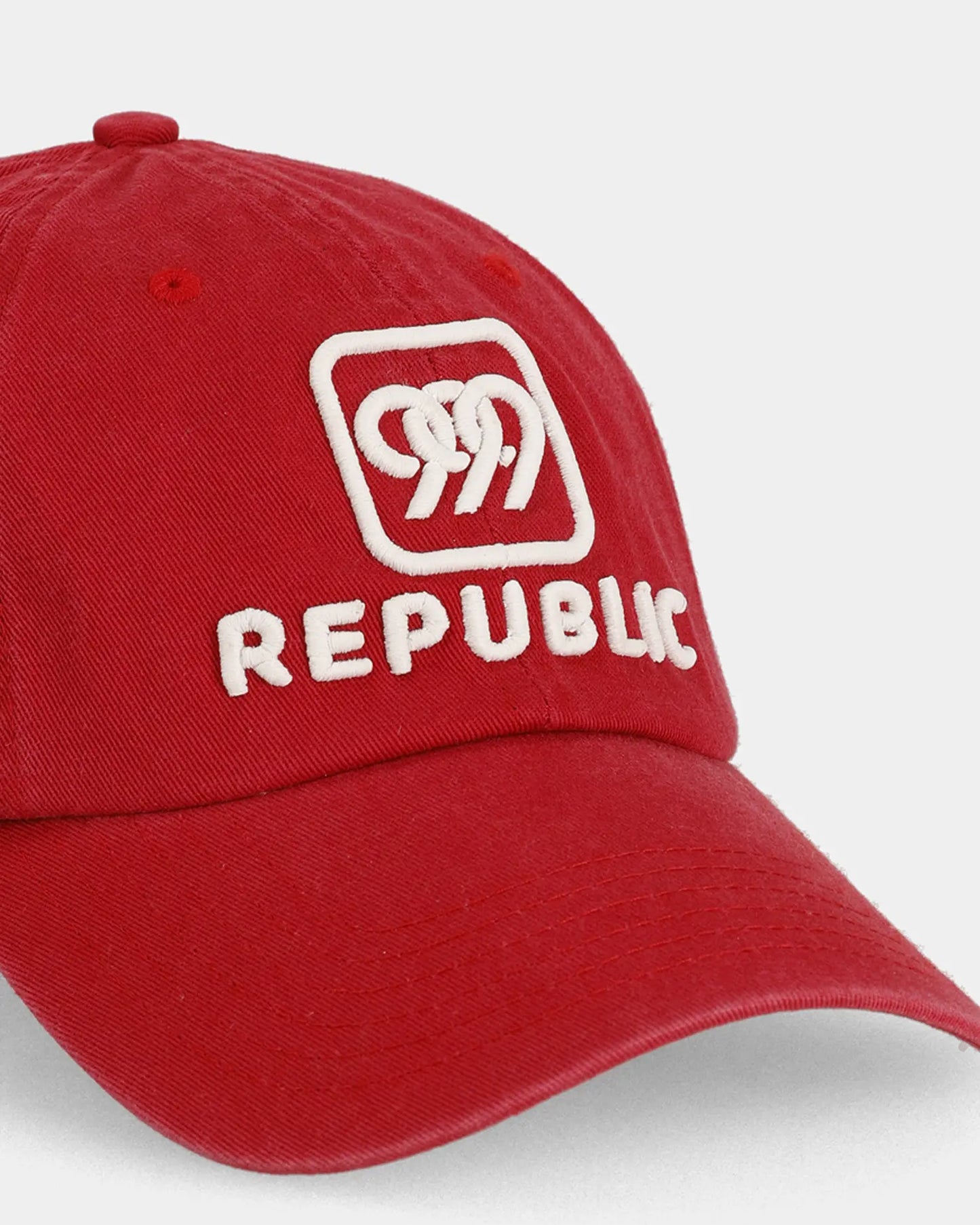 Red dad cap with white REPUBLIC embroidery, angled front detail view