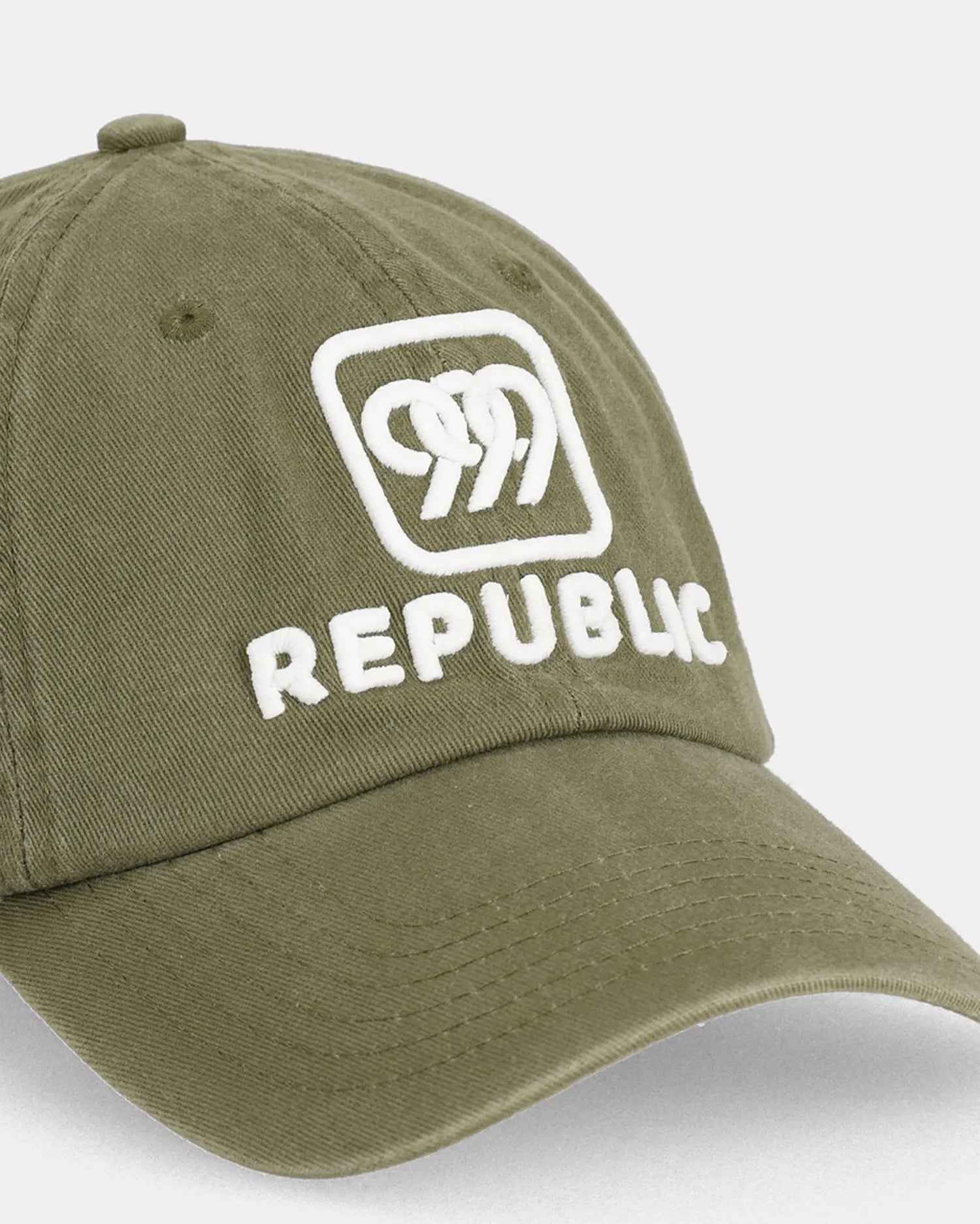 Olive dad cap with white REPUBLIC embroidery, angled front detail view
