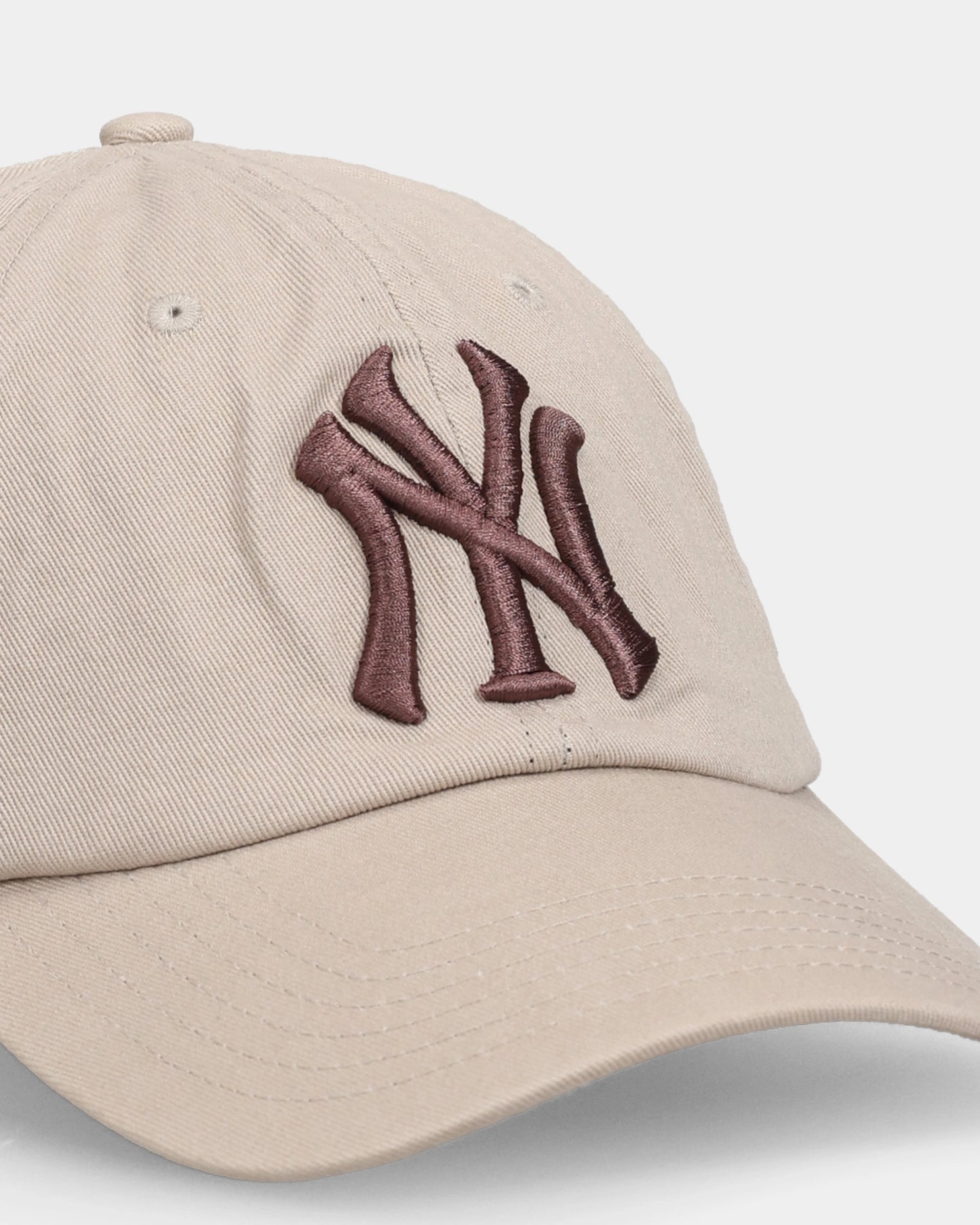 Khaki dad cap with raised 3D “NY” front embroidery, close-up front view
