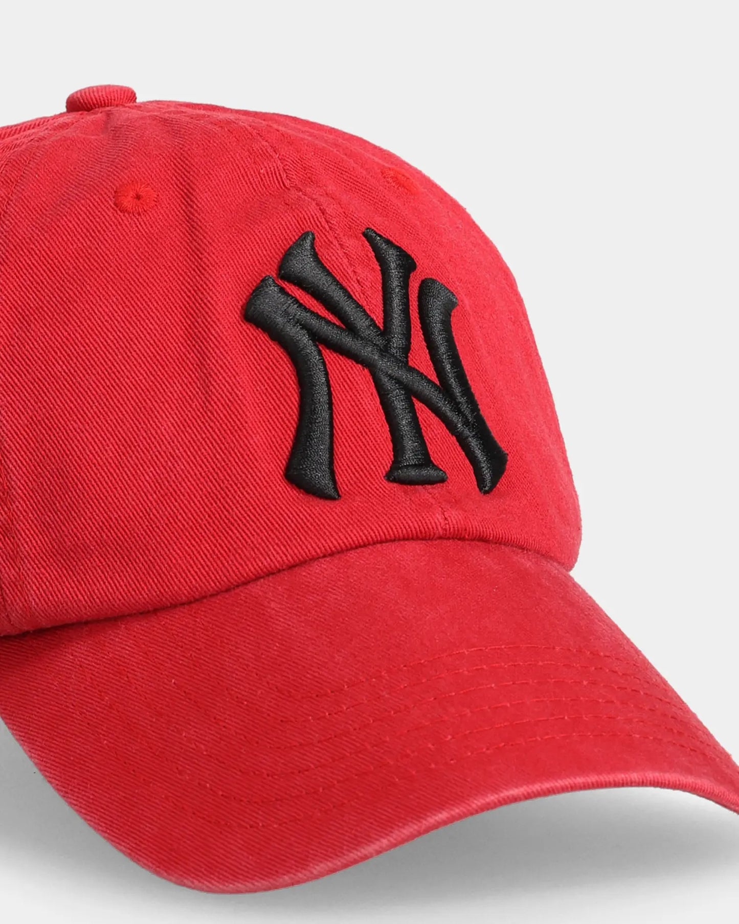 Red NY dad cap close-up with black embroidered front logo detail