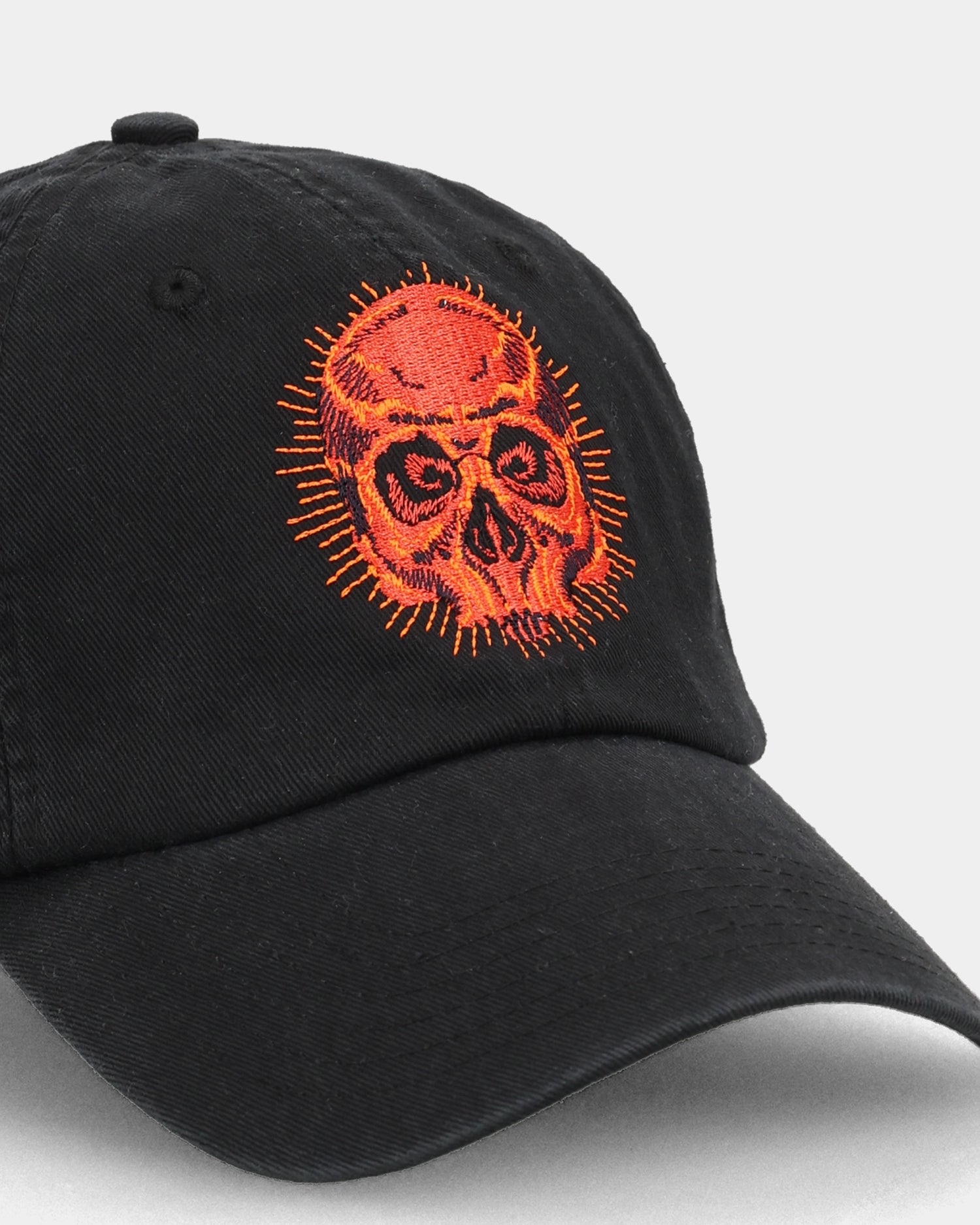 Black cap with red skull embroidery, angled close-up product shot.