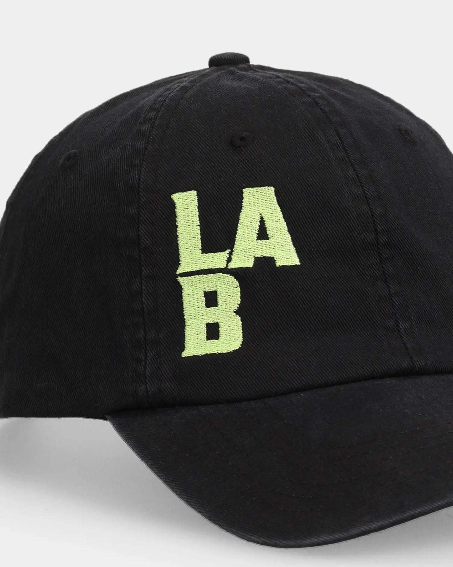 Black dad cap with green LAB embroidery, angled side product shot.