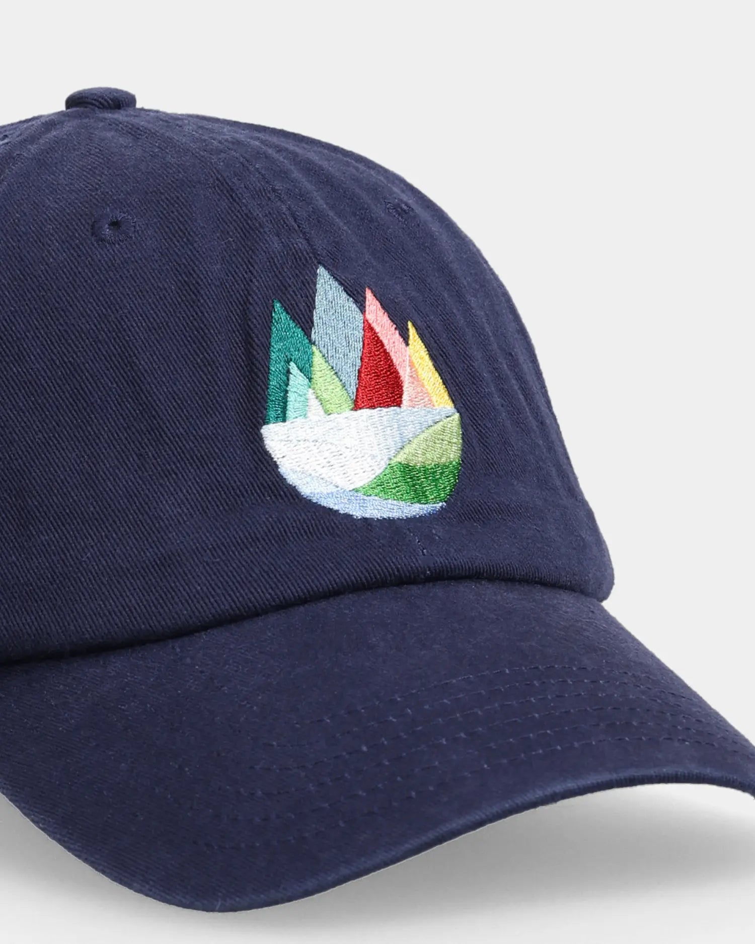 Navy dad cap with multicolour mountain embroidery, close-up angled view

