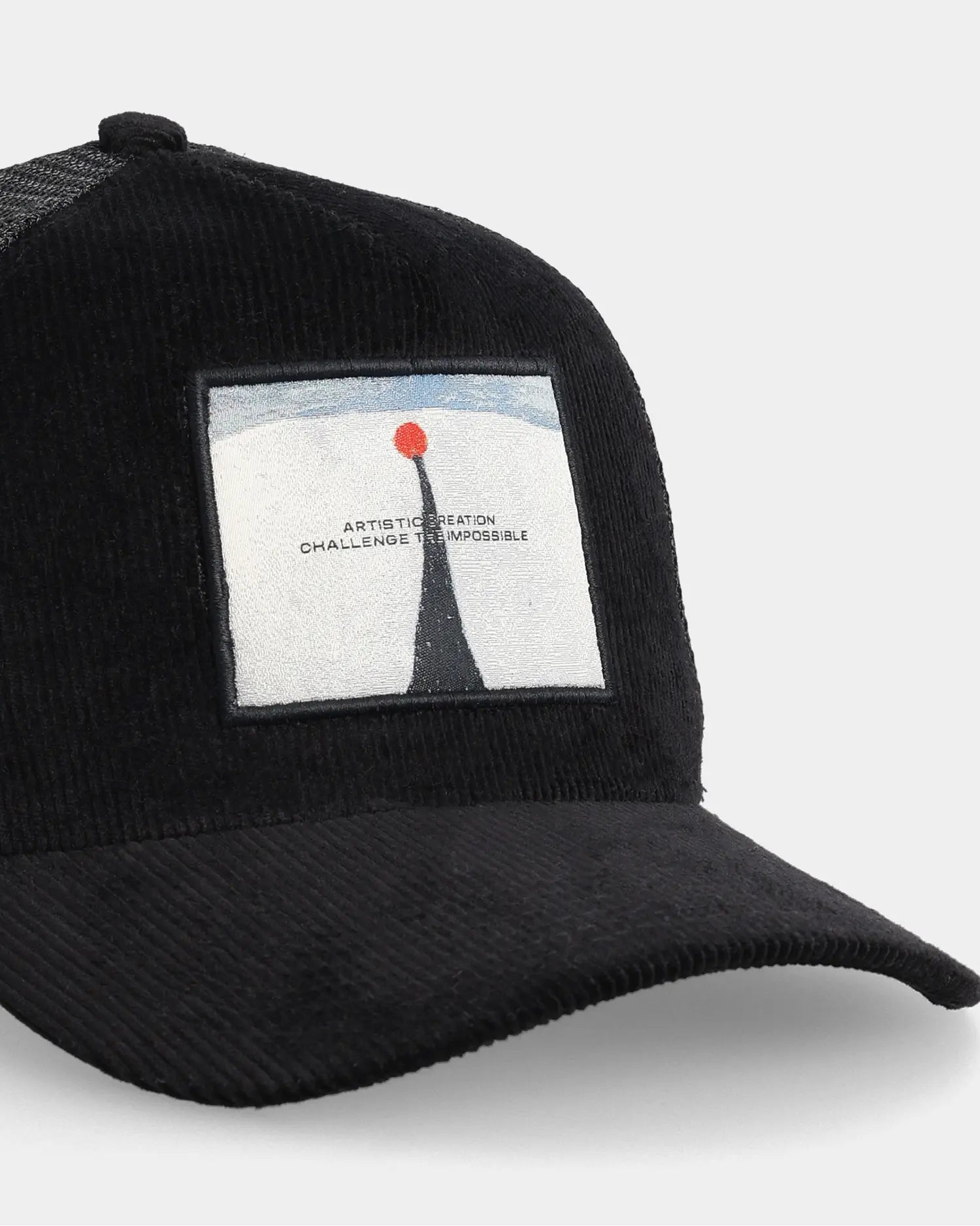 Black trucker cap with artistic creation patch, angled front detail view