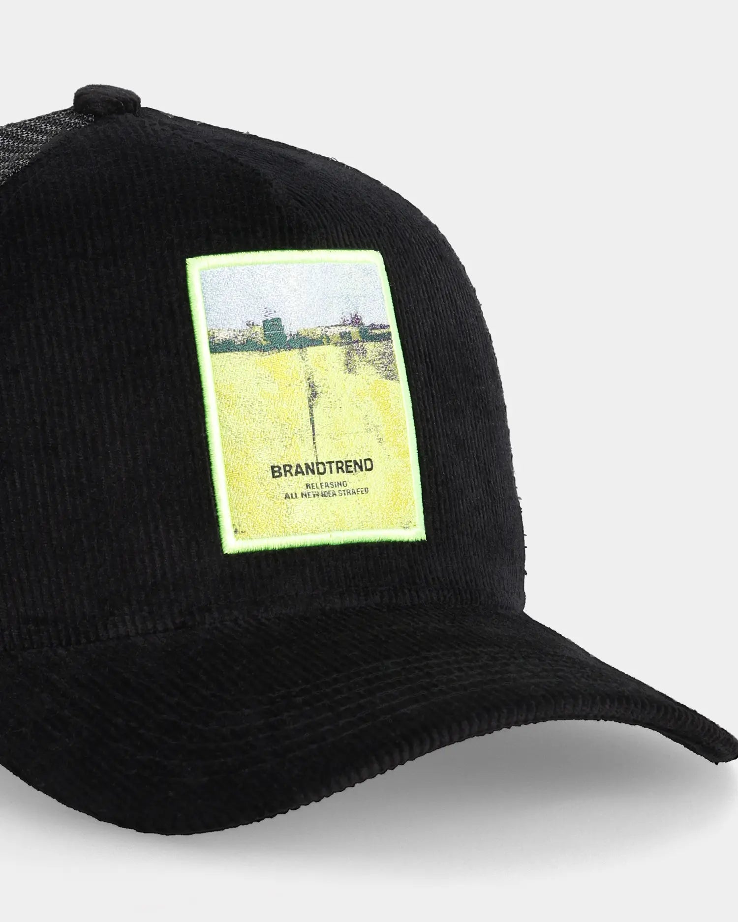 Black trucker cap with Brandtrend patch, angled front detail view