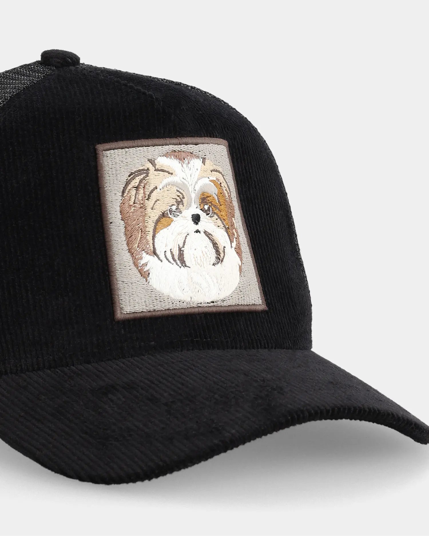 Black trucker cap with Shih Tzu dog patch graphic, angled front detail view