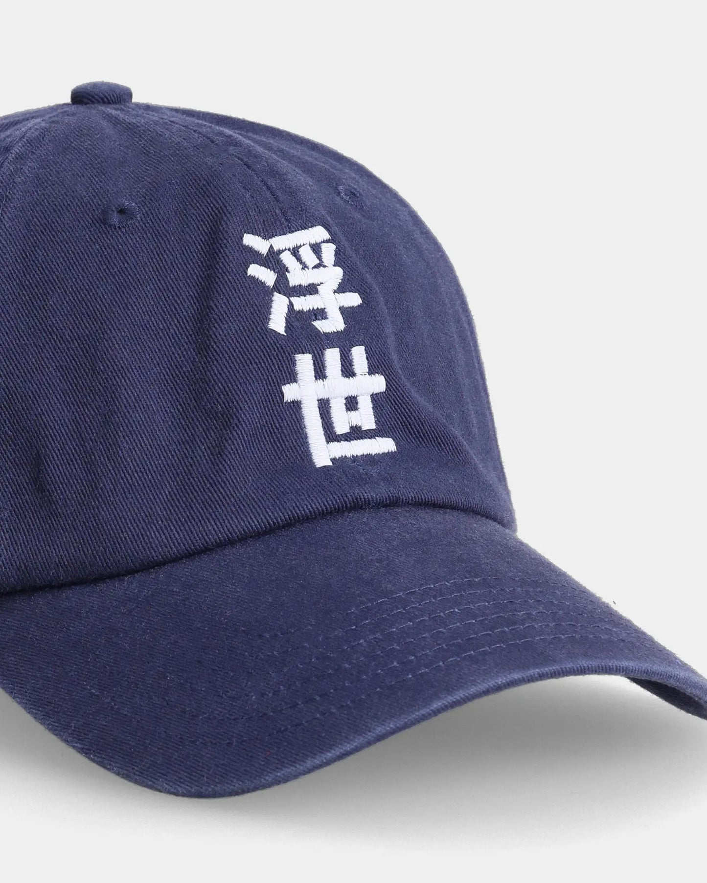 Navy dad cap close-up with white embroidered character detail