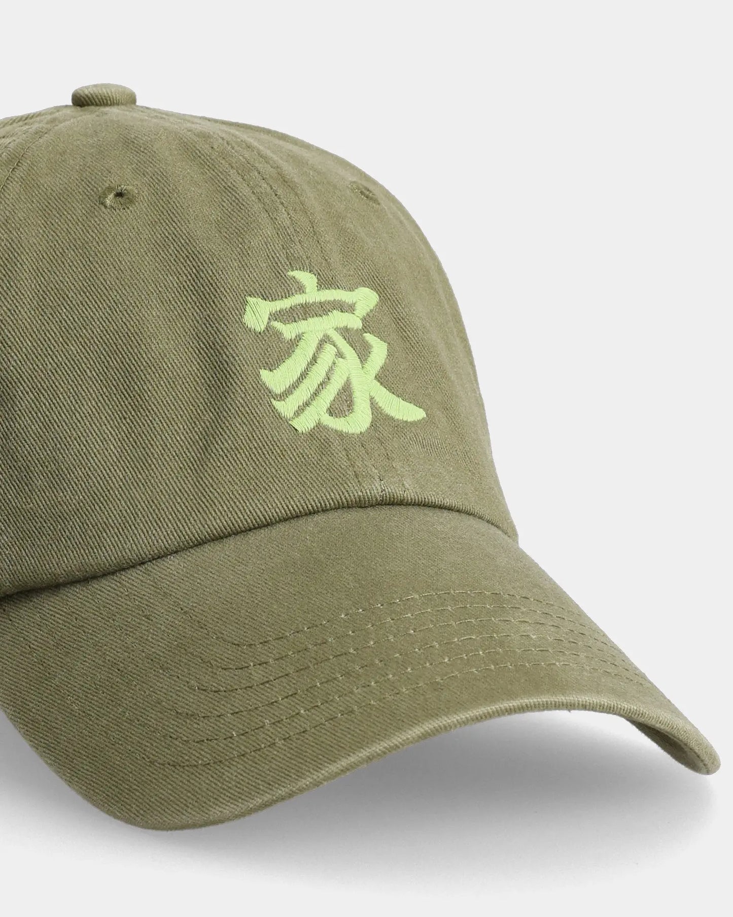 Olive IE dad cap close-up with embroidered character detail