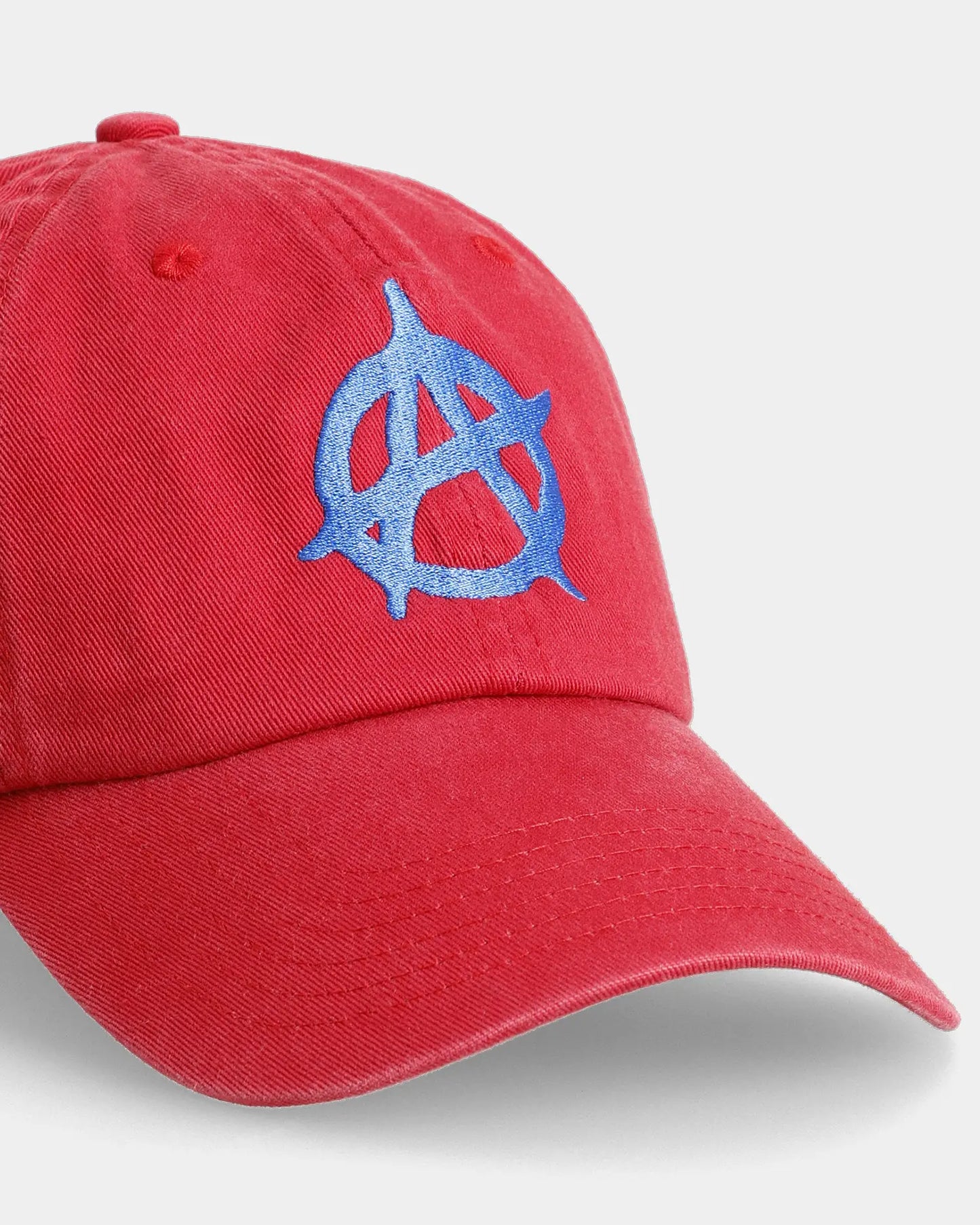 Red dad cap with blue anarchy embroidery, angled front close-up detail