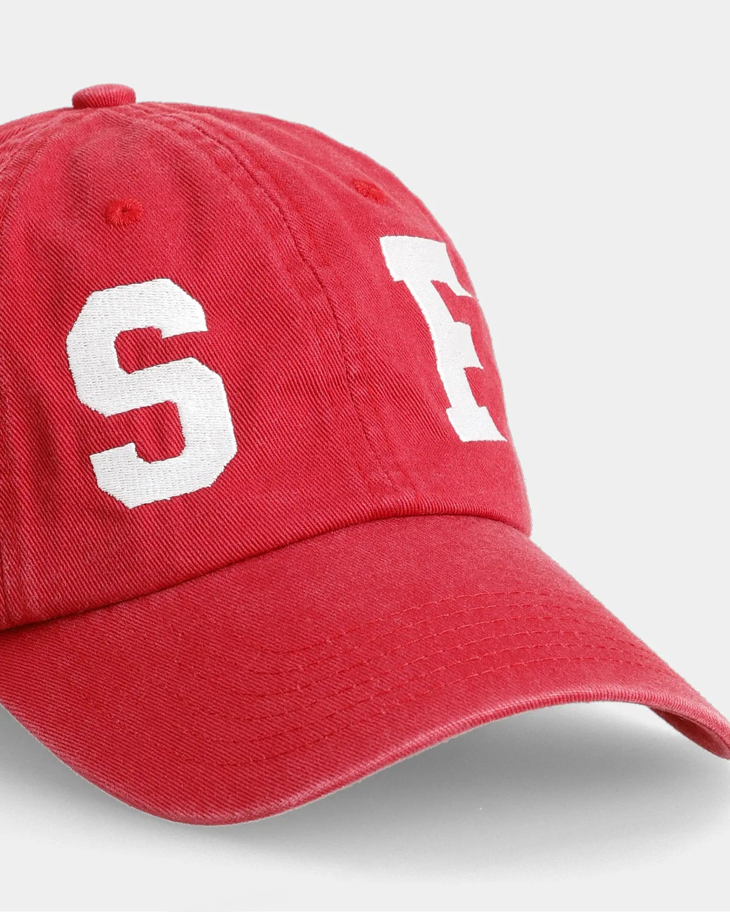 Red dad cap with SF letter embroidery, angled front close-up detail