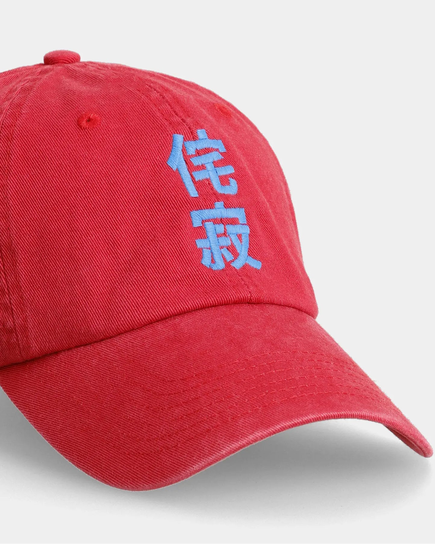 Red Wabi-Sabi Dad Cap with blue embroidery, angled front close-up