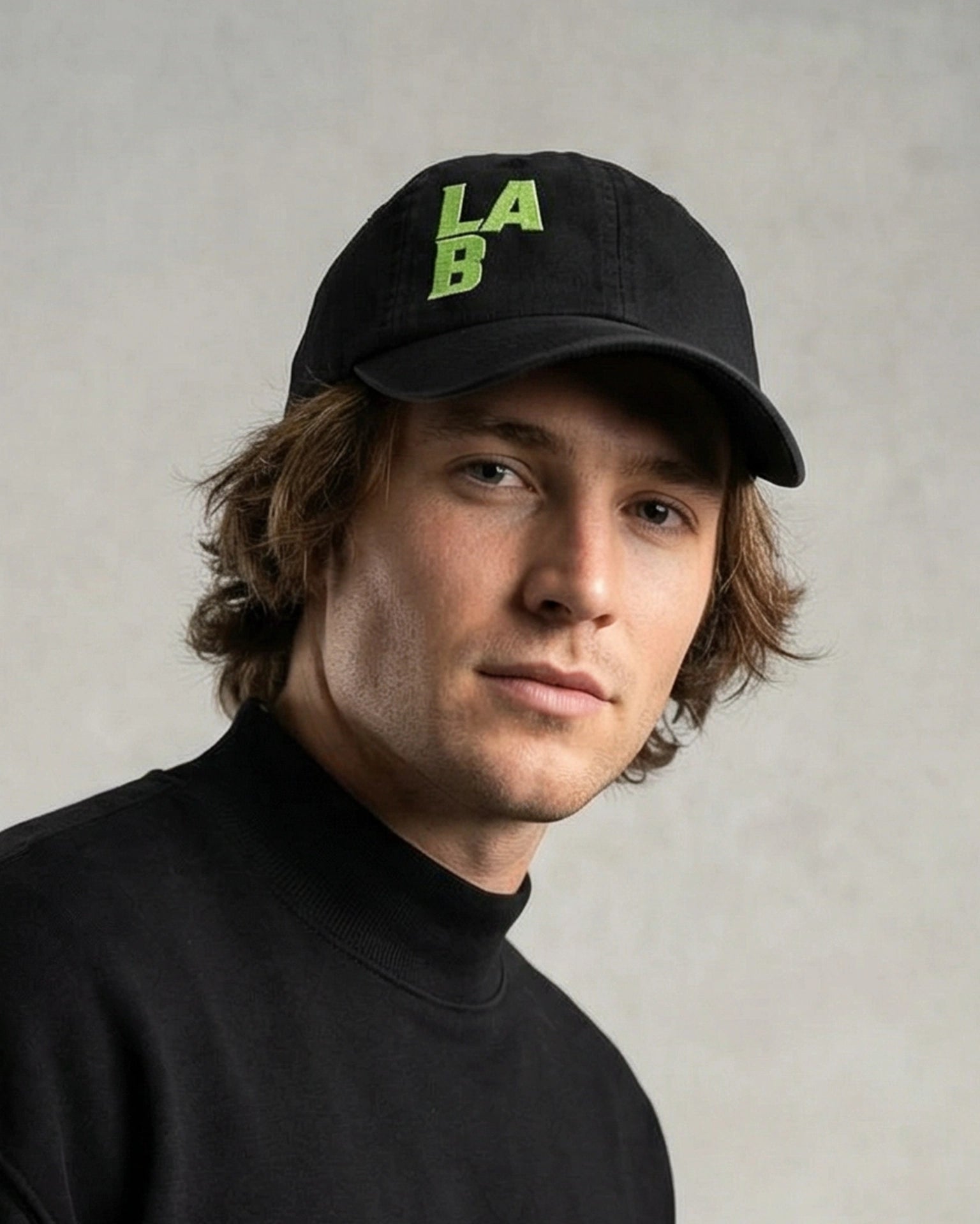 Model wearing a black dad cap with green LAB embroidery, close-up