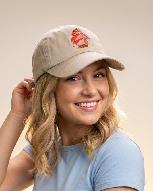 Female model wearing a khaki dad cap with “Sail Away” embroidery, styled in a clean studio setting against a neutral background.