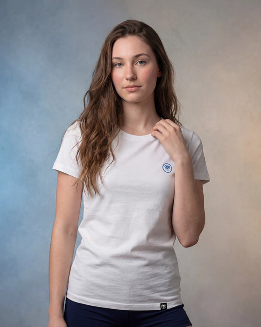Female model wearing white t-shirt with small blue circular logo, front view shot
