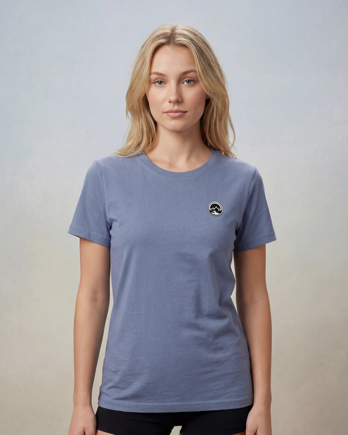 Model wearing blue t-shirt with circular mountain logo, front view model shot
