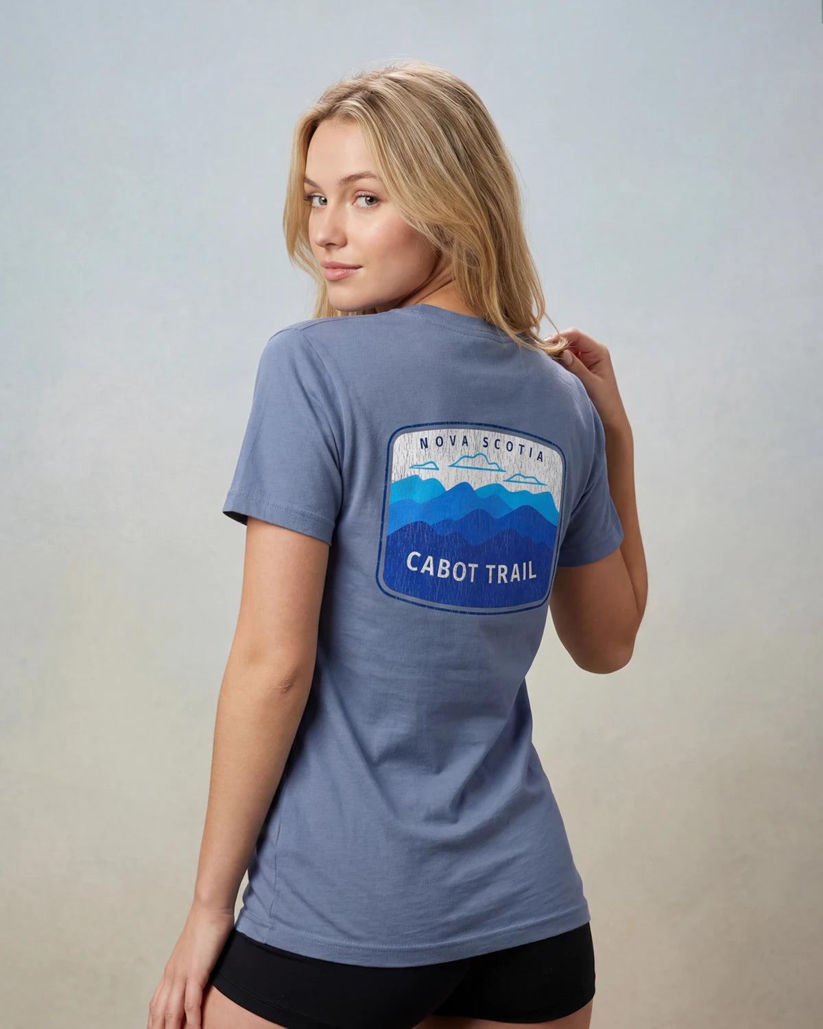 Model wearing blue t-shirt with NOVA SCOTIA CABOT TRAIL back graphic, back view
