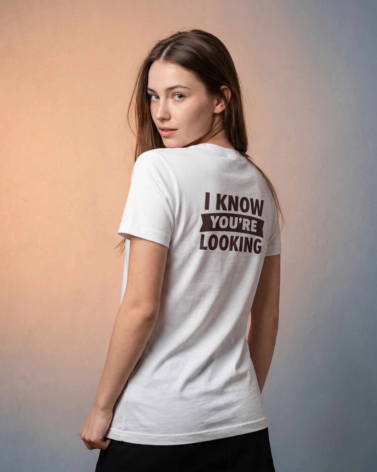 Model wearing white t-shirt with I KNOW YOU’RE LOOKING text, back view
