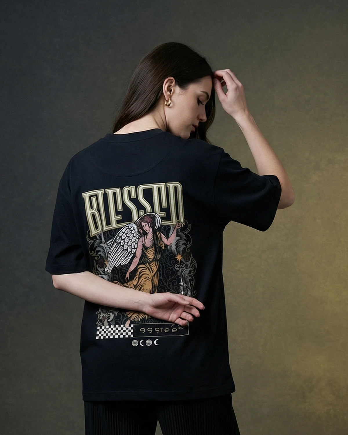 Female model wearing black oversized T-shirt with BLESSED angel graphic, back view