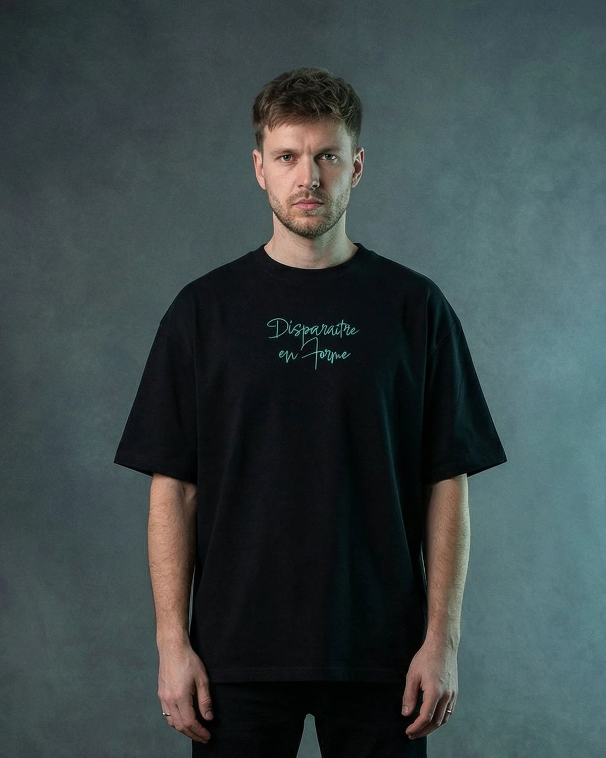 Male model wearing black oversized T-shirt with blue script text, front view