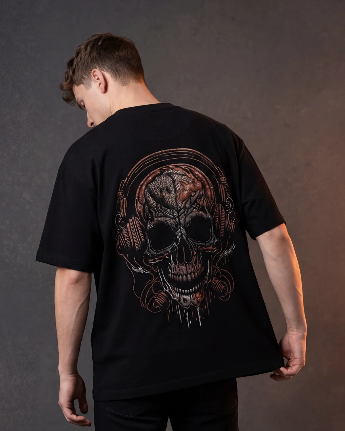 Male model wearing black T-shirt with skull headphone graphic, back view
