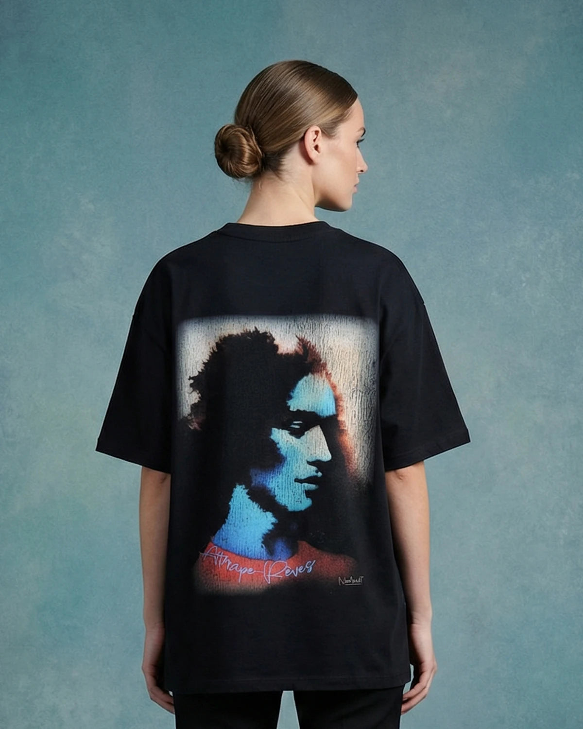 Female model wearing black dreamcatcher oversized T-shirt with portrait graphic, back view

