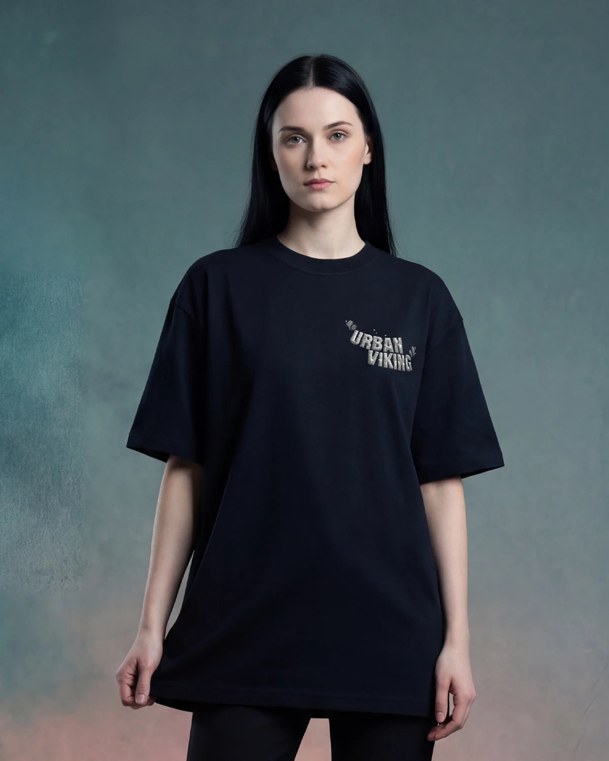 Female model wearing black oversized t-shirt with Urban Viking text logo on chest, front view
