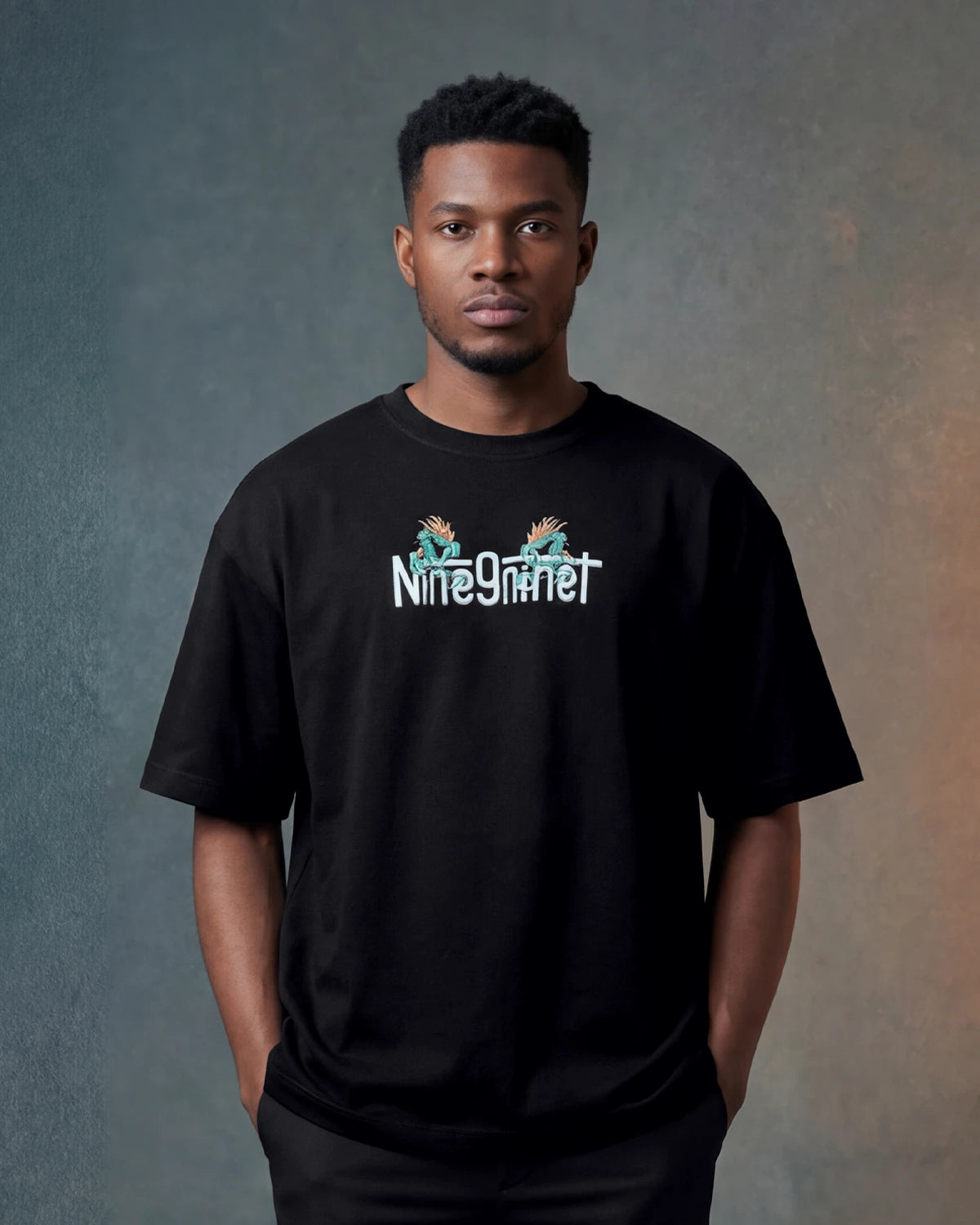 Male model wearing black oversized t-shirt with Dragon text logo on chest, front view
